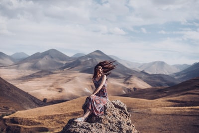 坐在岩石上的女人，头发被风吹动